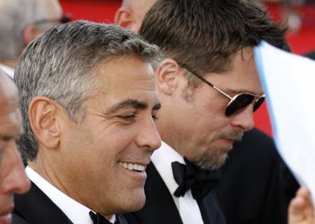 U.S. actor George Clooney (L) signs autographs next to Brad Pitt before a screening in Venice August 27, 2008.