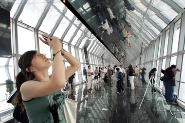 A visitor takes pictures on the 100th-floor observation deck of the 492-meter Shanghai World Financial Center yesterday. Boasting the world’s highest rooftop and highest observation deck, the building will open to the public tomorrow, 14 years after the project’s inauguration. 