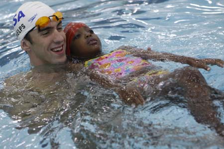 Olympic gold medallist Michael Phelps helps a girl as she swims at the YMCA of Greater New York in New York August 28, 2008.