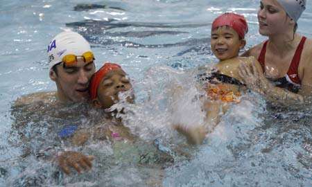Olympic gold medallist Michael Phelps helps a girl as she swims at the YMCA of Greater New York in New York August 28, 2008.