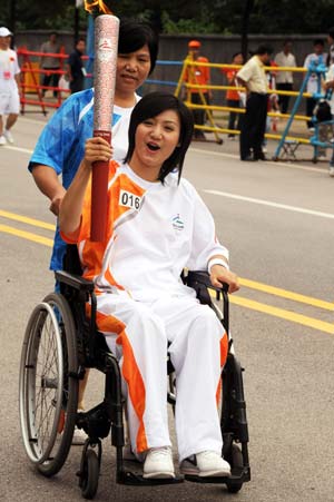 Torchbearer Liang Qiong holds the torch in a wheelchair during the Beijing 2008 Paralympic torch relay in Changsha, capital of central China's Hunan Province, China, Aug. 31, 2008.