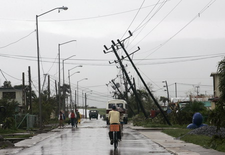 People pass a street with damaged power lines in the aftermath of Hurricane Gustavin in Los Palacios, Cuba August 31, 2008. Gustav moved into the oil-rich Gulf of Mexico on Saturday where it was expected to strengthen and threaten New Orleans after its 150 mile per hour (240 kph) winds cut a swath of destruction through western Cuba. [Agencies] 