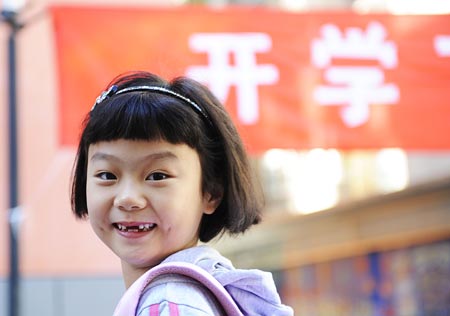 A grade one pupil poses for the photographer as she walks into the Beijing No. 2 Experimental Primary School in Beijing, capital of China, Sept. 1, 2008. Middle schools and primary schools started the new semester in China on Monday. (Xinhua/Wu Xiaoling) 