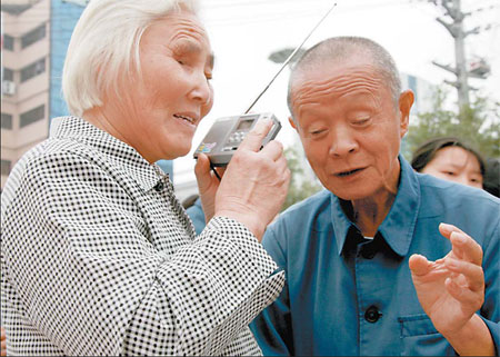 We're all ears: A blind couple listens to a radio yesterday in Huangshan, Anhui province. The city's disabled people's association and a local radio station got together to donate 350 radios to poor blind people so they can listen to programs about the Paralympics. [Shi Guangde/China Daily]