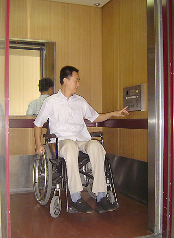 A wheelchair-user takes a modified lift at Benevolence Hospital in Beijng on August 28, 2008.The hospital, including elevators and bathrooms, has been modified for use by disabled people.[Xinhua]