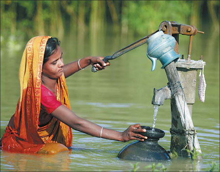 A woman collects drinking water from a pump in the flooded village of Godadhar in Faridpur, Bangladesh. Reuters