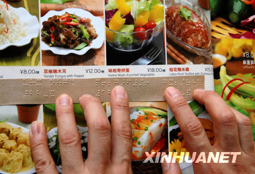 A diner reads a Braille menu at a restaurant in Beijing on September 2, 2008. As the Paralympic Games draw near, the city's service industry is striving to provide more convenient services for the disabled. [Photo: Xinhuanet]