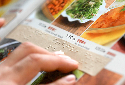 A diner reads a Braille menu at a restaurant in Beijing on September 2, 2008. As the Paralympic Games draw near, the city's service industry is striving to provide more convenient services for the disabled. [Photo: China Foto Press]