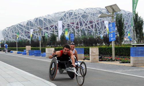 Two Paralympic athletes in their wheelchairs pose in front of the National Stadium or 'Bird's Nest' in Beijing, September 3, 2008. The Beijing Paralympic Games will kick off on Saturday. [Xinhua]