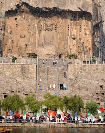 Local residents cheer for the Paralympic torch relay of the Luoyang leg in front of the Long Men Grottes, one of the tour destinations of the city in Central China's Henan Province September 4, 2008. [Xinhua] 