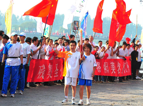 Guo Jie (L) bears the Paralympic torch with the help of a volunteer during the Luoyang leg in Central China's Henan Province September 4, 2008. [Xinhua]