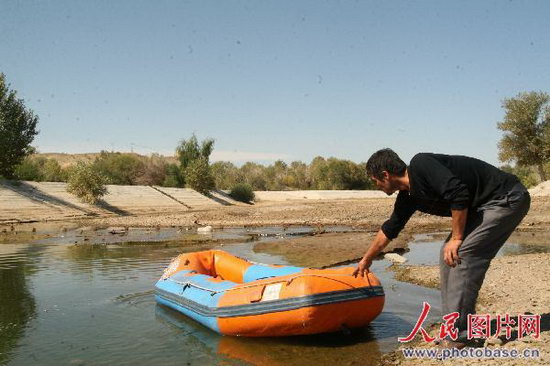 A hiker pulls a raft from the dry riverbed at Baiyanghe Canyon scenic area in Kalamay, Xinjiang Uygur Autonomous Region, on September 2, 2008. The most severe drought in ten years currently threatens the city in northwestern China. [Photo: Photobase.cn]