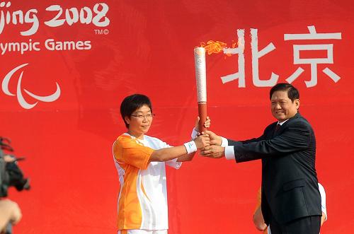 The first torchbearer Wang Juan receives the torch from BOCOG President Liu Qi. [Xinhua] 