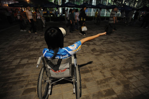A Paralympic volunteer in a wheelchair uses a bullhorn to guide spectators attending the reheasal for the opening ceremonies of the 2008 Paralympic Games, September 4, 2008. [Xinhua] 
