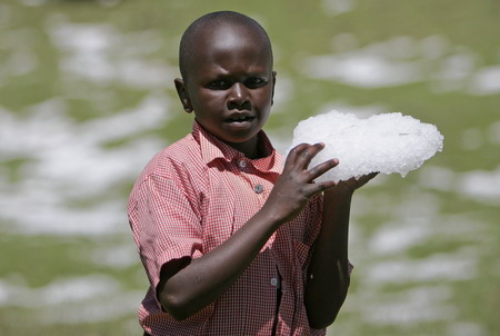 A boy holds a block of ice after heavy hailstorms hit a deforested hillside in Gikingi Village in Nyahururu town, some 220km from Nairobi, September 3, 2008. [Agencies]