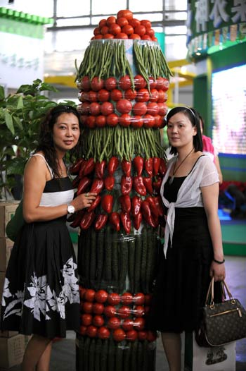 Visitors pose for photos with a tower decorated with vegetables at the 2008 Kunming International Agriculture Exposition in Kunming, southwest China's Yunnan Province, Sept. 4, 2008. Green food and pollution-free vegetables are customers' favorite at the Exposition held along with the 2008 Kunming International Flower Exhibition. [Xinhua] 