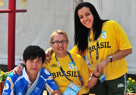 Athletes of Brazil have a group photo taken with a Chinese volunteer (L) at the Paralympic Village in Beijing on September 5, 2008. Athletes and delegates from all over the world gathered in Beijing to attend the Beijing 2008 Paralympic Games which will be opened on September 6, 2008. 