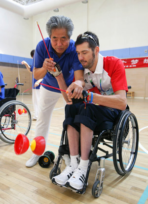 A German athlete (R) tries to play a diabolo at a community gymnasium reserved for the disabled in Dongsi Community in Beijing, capital of China, September 5, 2008. Ten German athletes who are in Beijing to take part in the Beijing 2008 Paralympic Games visited the Community on Friday.