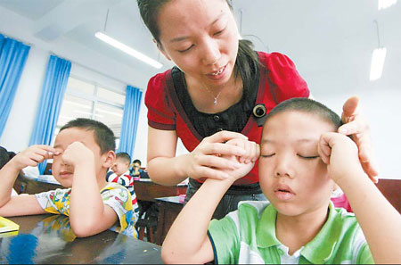 A teacher shows first grade students how to perform eye exercises on Monday at Hongqi Primary School in Chongqing municipality. Chen Shichuan