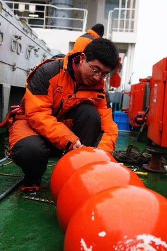 A scientist removes equipment from a shallow-sea subsurface mooring system on China's icebreaker Xuelong at the North Pole on September 8, 2008. The system was installed one month ago to collect hydrological data of the region. [Photo: Xinhua]