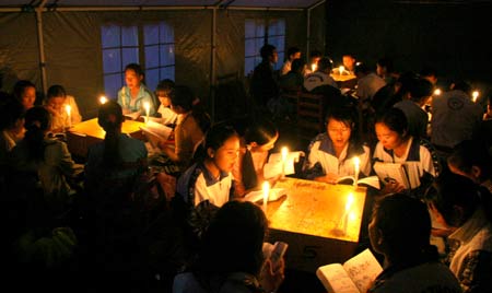 Students read books through candle light in a tent in the No.1 Middle School of the quake-hit Yongren County, southwest China's Yunnan Province, Sept. 3, 2008. School buildings and dormitories of the middle school were badly damaged in the 6.1-magnitude earthquake which hit Panzhihua and Huili in Sichuan Province and the neighboring Yunnan Province on Aug. 30. Hence, the school has postponed its new semester to Sept. 5 and built 28 tent classrooms for temporary use on its playground.[Chen Haining/Xinhua]