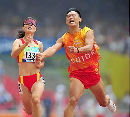 China's Wu Chunmiao (L) runs with the guide during the final of the women's 100m T11 of the Beijing 2008 Paralympic Games, at the National Stadium, also known as the Bird's Nest, in Beijing, China, Sept. 9, 2008. Wu claimed the title of the event with a time of 12.31 seconds. 