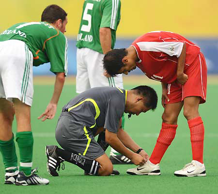 Chinese referee Fu Xiangyang ties the shoelace for an Iranian footballer at the Beijing 2008 Paralympic Games in Beijing, China, Sept. 8, 2008. 