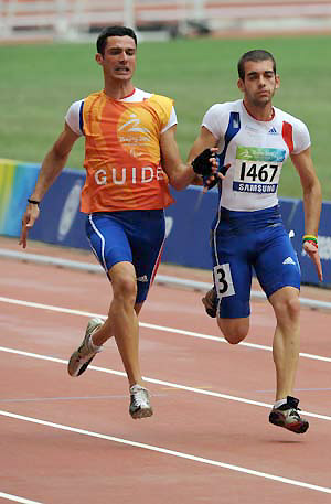 France's Pasquale Gallo (R) competes with the guide during the first round competition of the men's 100M T12 at the National Stadium，also known as the Bird's Nest, at the Beijing 2008 Paralympic Games in Beijing, China, Sept. 8, 2008. 