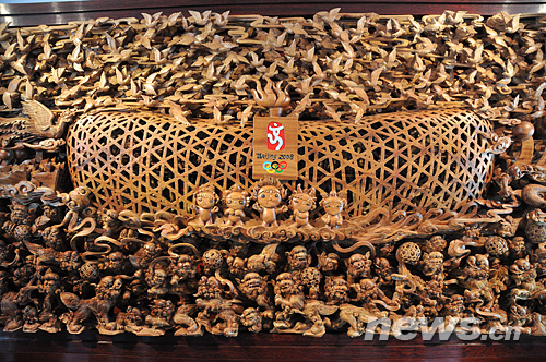 A Chaozhou woodcarving showing the pattern of the 'Bird's Nest' attracts visitors in Guangdong House.