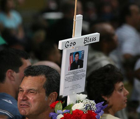 A citizen holds the photo of a fireman who lost his life in the Sept. 11 attacks at the site of the former twin World Trade Center towers in New York, Sept. 11, 2007. New York citizens Tuesday gathered here in rain to attend the ceremony marking the sixth anniversary of the tragedy.