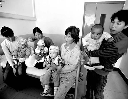 Infants made ill by the contaminated milk sit with their parents Wednesday at the No 1 Hospital of the People's Liberation Army in Lanzhou, Gansu province. [China Daily]