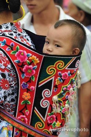 A baby sits in his mother's home-made carrier in Jichang Shui autonomous town, Guizhou province September 7, 2008. [Asianewsphoto]