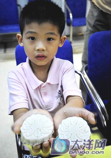 A child displays a homemade moon cake in on Tuesday, September 9, 2008. [Photo: dayoo.com]