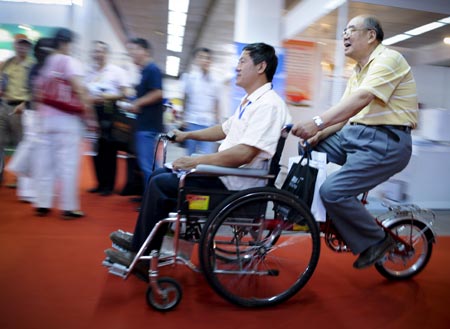 People try a multifunctional wheelchair during a visit to an exhibition for the rehabilitative and assistive facilities held in Beijing September 11, 2008. The three-day expo, started on Thursday, will display more than 1,000 types of products for the physically challenged like hearing aids, special vehicles for the disabled, prosthetic limbs and diapers for the paralyzed.(Xinhua/Liu Jie) 