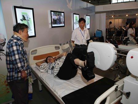 A staff member (C)introduces a rehabilitative facility to visitors at an exhibition for the rehabilitative and assistive facilities held in Beijing September 11, 2008. The three-day expo, started on Thursday, will display more than 1,000 types of products for the physically challenged like hearing aids, special vehicles for the disabled, prosthetic limbs and diapers for the paralyzed.(Xinhua/Yuan Man)