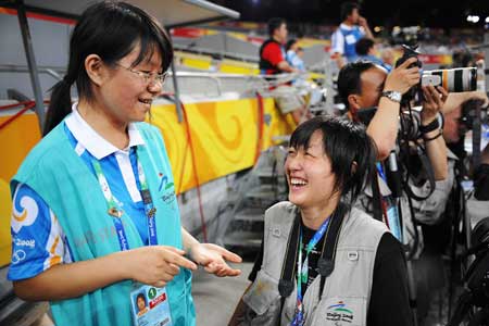 Zhao Dan (L), a Peking University student from China's quake-hit Sichuan Province, helps a Japanese photographer at the National Stadium Sept. 11, 2008.