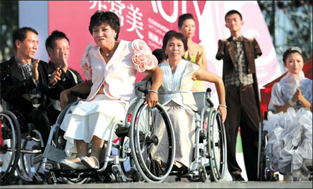 Disabled models show off clothes designed by teachers and students from the Beijing Institute of Fashion Technology at a special fashion show held yesterday at the Olympic Green. [Lu Zhongqiu/China Daily] 