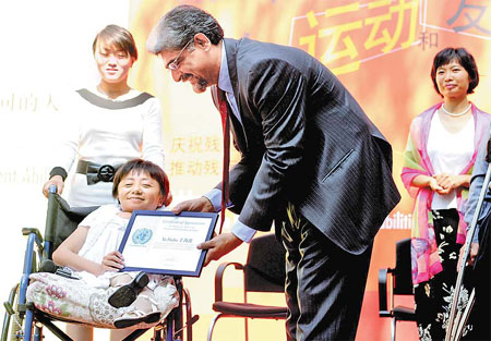 United Nations Resident Coordinator in China Khalid Malik presents a certificate to Yu Haibo, founder of the Changchun Xinyu Volunteer Association, in Beijing yesterday. The association focuses on helping the disabled. [Lu Zhongqiu/China Daily] 
