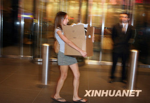 An employee walks out of the headquarter for Lehman Brothers in New york with her belongings on Sep. 14, 2008. [Xinhua]