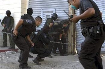 Federal police officers guard a door to La Mesa state penitentiary during a prison riot in Tijuana, Mexico, Sunday, Sept. 14, 2008. Prisoners were angered by the alleged deaths of inmates at the hands of guards, and at least four prisoners were injured.[Guillermo Arias/AP]