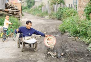 This undated photo shows Guo Wen, a wheel-chaired 58-year-old man paves a road by carrying stones in a basin.[photo:sohu.com] 