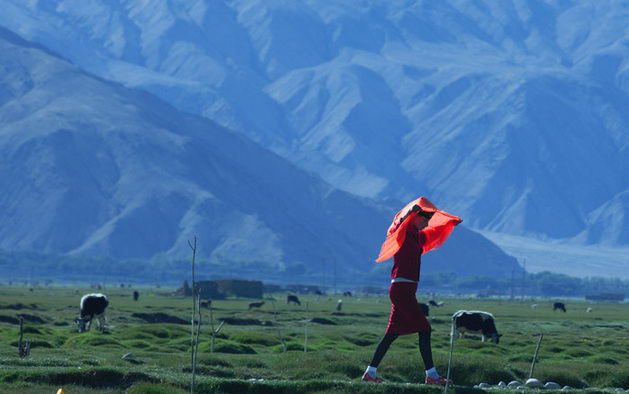 Red scarf is a splash of color against the mountains and grassland. 