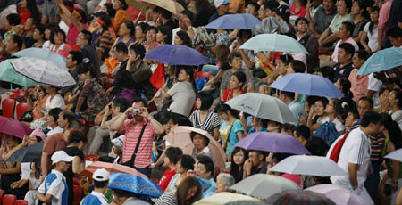 Audience watch the athletics match in the heavey rain at the National Stadium, also known as the Bird's Nest, during the Beijing 2008 Paralympic Games in Beijing, Sept. 16, 2008.
