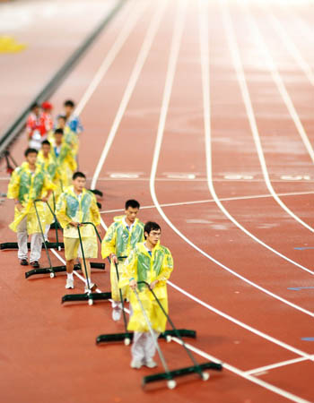 Staff members clear the track after a heavey rain at the National Stadium，also known as the Bird's Nest, during the Beijing 2008 Paralympic Games in Beijing, Sept. 16, 2008. 