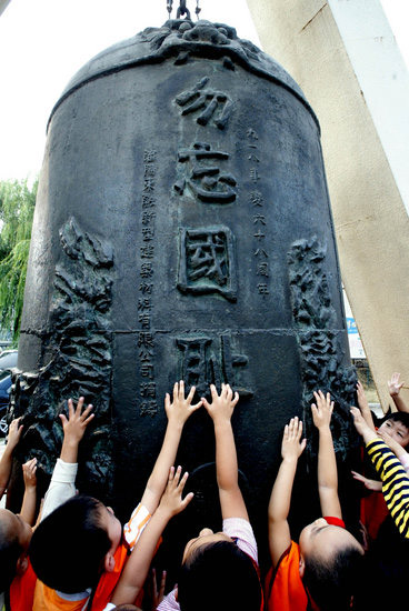 Children touch a bell designed in an attempt to alarm the people not to forget the day in the history at the September 18 History Museum in Shenyang, Northeast China's Liaoning Province September 17, 2008. [Photo: CFP] 