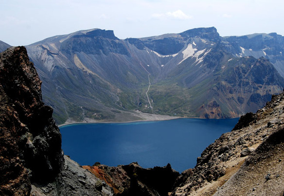 The lake is hugged by scarred and rugged mountains. 