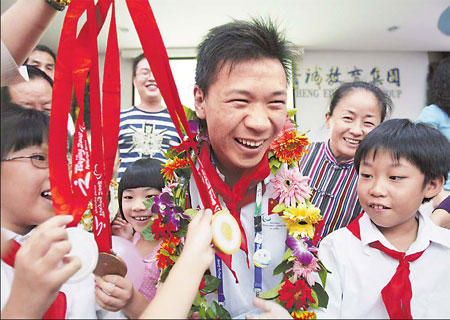 Paralympic swimming star He Junquan shows off his two gold and one silver medals to students at Beijing Jingcheng Primary School yesterday. He had earlier spoken to the children about what it takes to become a champion athlete. [Xinhua]