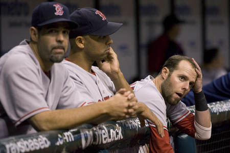 Boston Red Sox Dustin Pedroia (R) watches his teammates bat, alongside the Red Sox Alex Cora (C) and Mike Lowell, during the ninth inning of their American League MLB baseball game against the Tampa Bay Rays in St. Petersburg, Florida September 17, 2008. 
