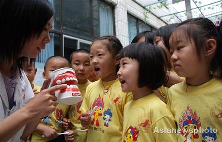 A dentist shows pupils the correct way to brush their teeth at Shizhong District Experimental Primary School in Zaozhuang, Shangdong province, to mark the country's Teeth Care Day on September 20, 2008. [Asianewsphoto]