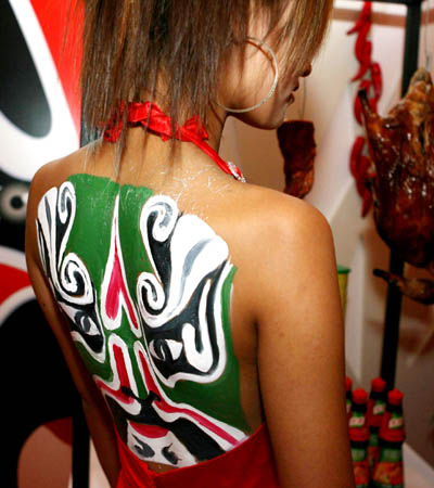 A model with coloured pattern on her back helps to recommend at a booth of Sichuan cuisine during 2008 Autumn/Winter Food Fair in Shanghai, China on Sep. 17, 2008. Some 150 chefs participated in the fair to show their unique cuisine. (Xinhua/Zhang Ming)